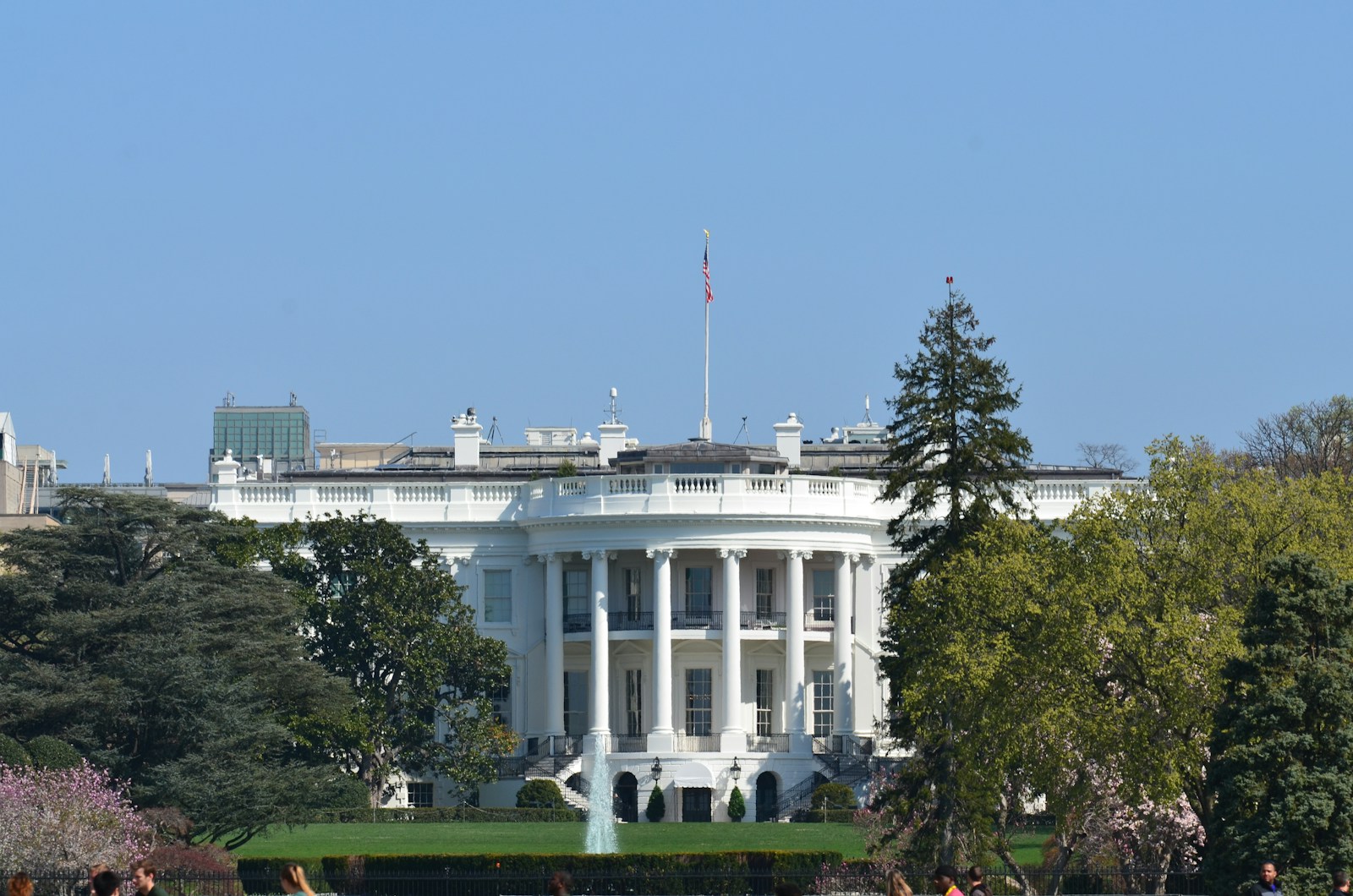 white concrete building near green trees under blue sky during daytime