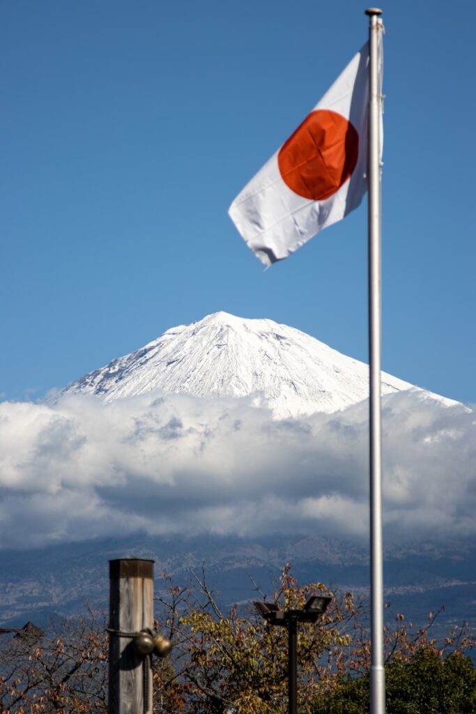 a japanese flag flying in front of a mountain