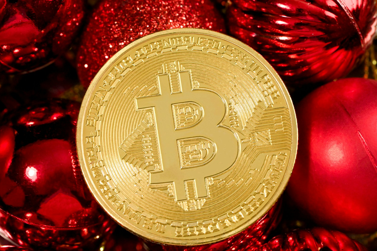 a bitcoin surrounded by christmas ornaments