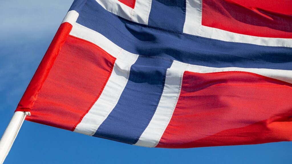 a flag flying in the wind with a blue sky in the background