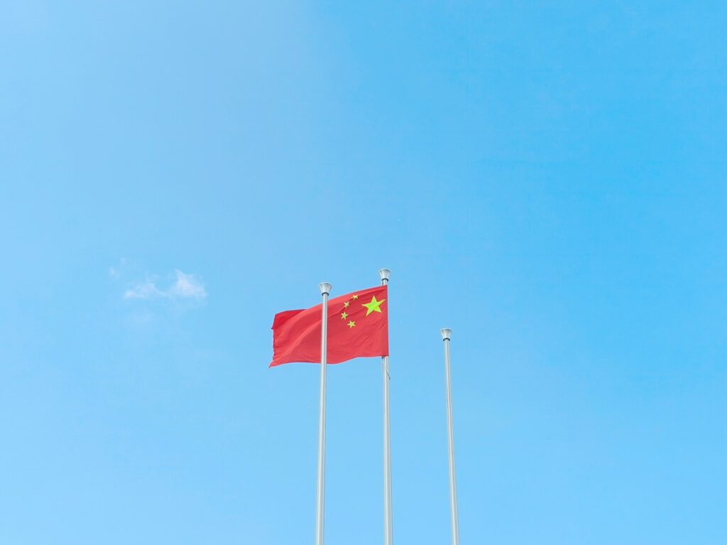 Two flags flying in the wind on a sunny day