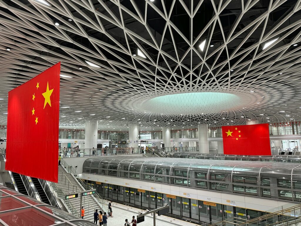 a train station with a train and a flag hanging from the ceiling