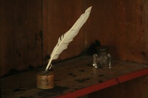 Quill pen in an inkwell on a wooden desk.