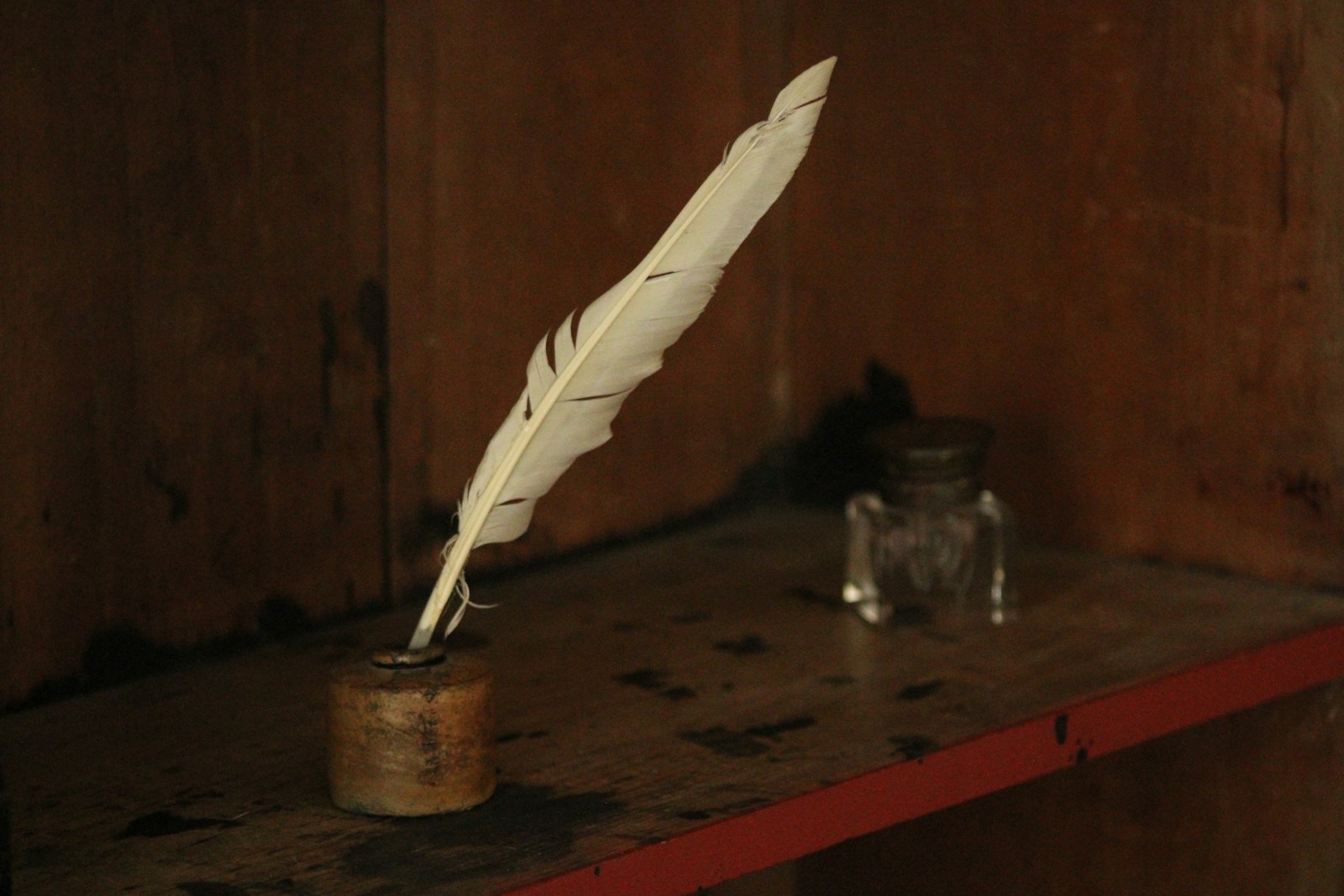 Quill pen in an inkwell on a wooden desk.