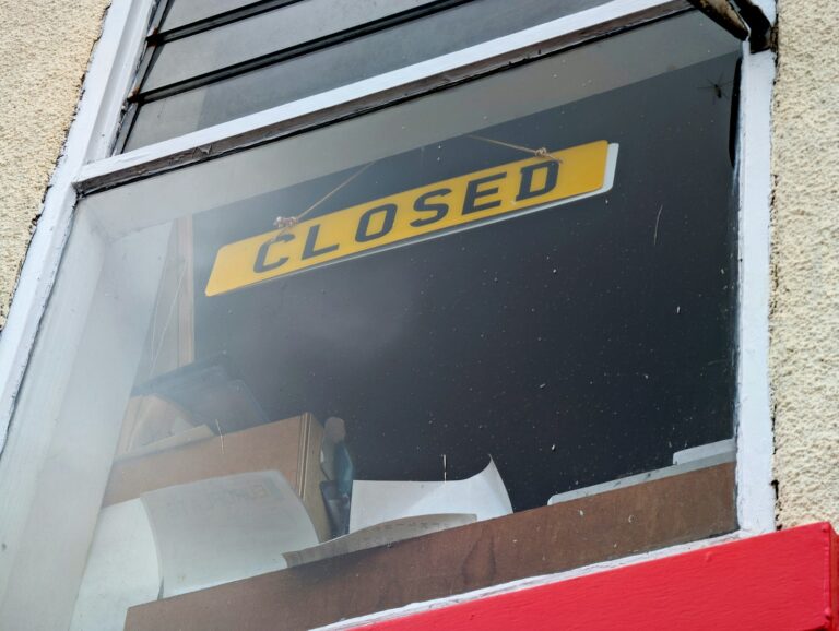 A yellow sign reads closed in a window.