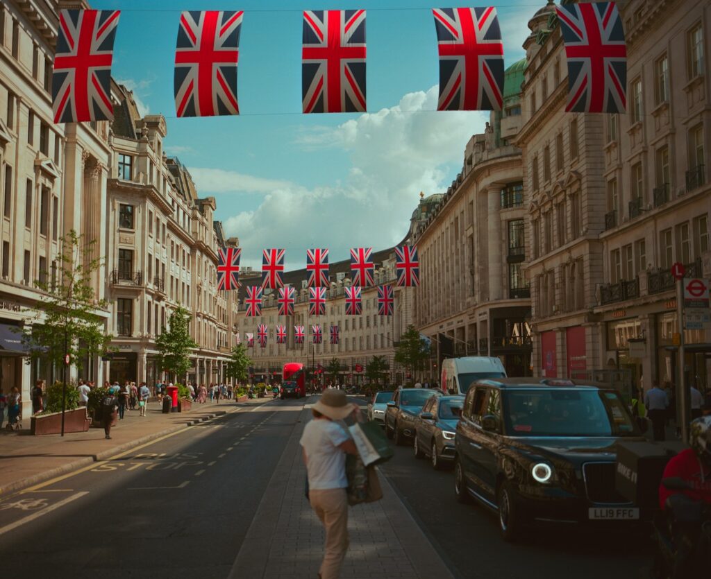 Union jack flags adorn a london street with people.