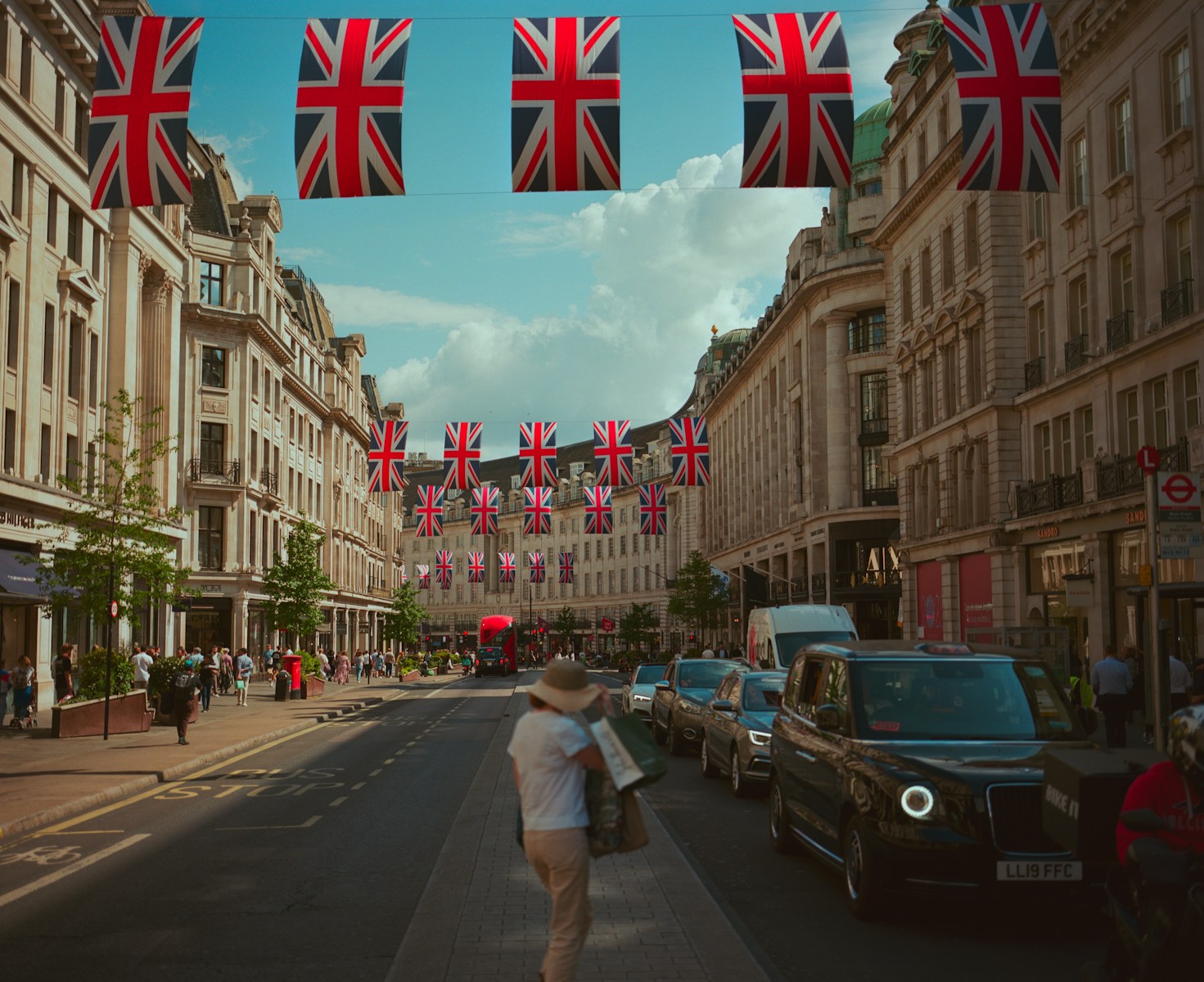 Union jack flags adorn a london street with people.