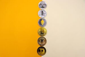 A row of cryptocurrency coins including Bitcoin, Ethereum, and Dogecoin on a vibrant yellow surface.