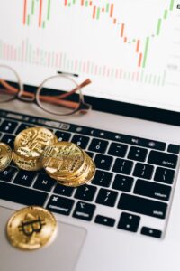 Gold bitcoins on a laptop with a financial chart, symbolizing cryptocurrency and investment trends.