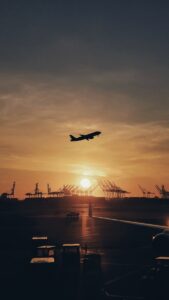 silhouette of airplane flying over the people during sunset