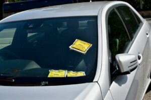 Silver car with yellow parking tickets on its windshield