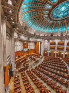 Stunning view of a grand neoclassical parliament chamber with intricate dome ceiling and seating arrangement.