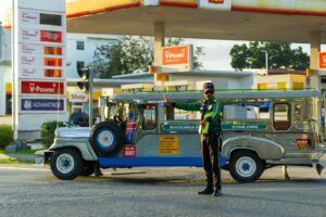 Traffic officer signals jeepney at a fuel station in the Philippines with clear weather and dynamic setting.