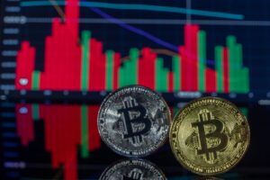 Two Bitcoin coins in front of a financial chart showcasing cryptocurrency trading trends.