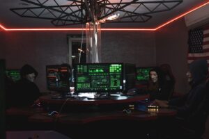 Team of hackers with Guy Fawkes masks coding in a dark room with computers.