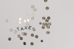 A visually striking flatlay of coins with 'Taxes' text on a white surface, ideal for financial concepts.