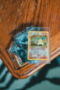 A set of valuable Pokemon trading cards displayed in protective cases on a wooden table.