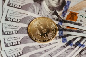 Gold Bitcoin coin resting on US dollar bills showcasing digital and traditional currency.