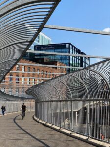 Sunlit footbridge with skyline in Glasgow, Scotland, showcasing urban architecture.