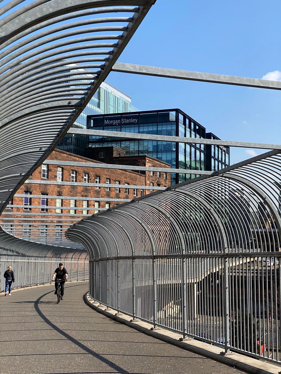 Sunlit footbridge with skyline in Glasgow, Scotland, showcasing urban architecture.