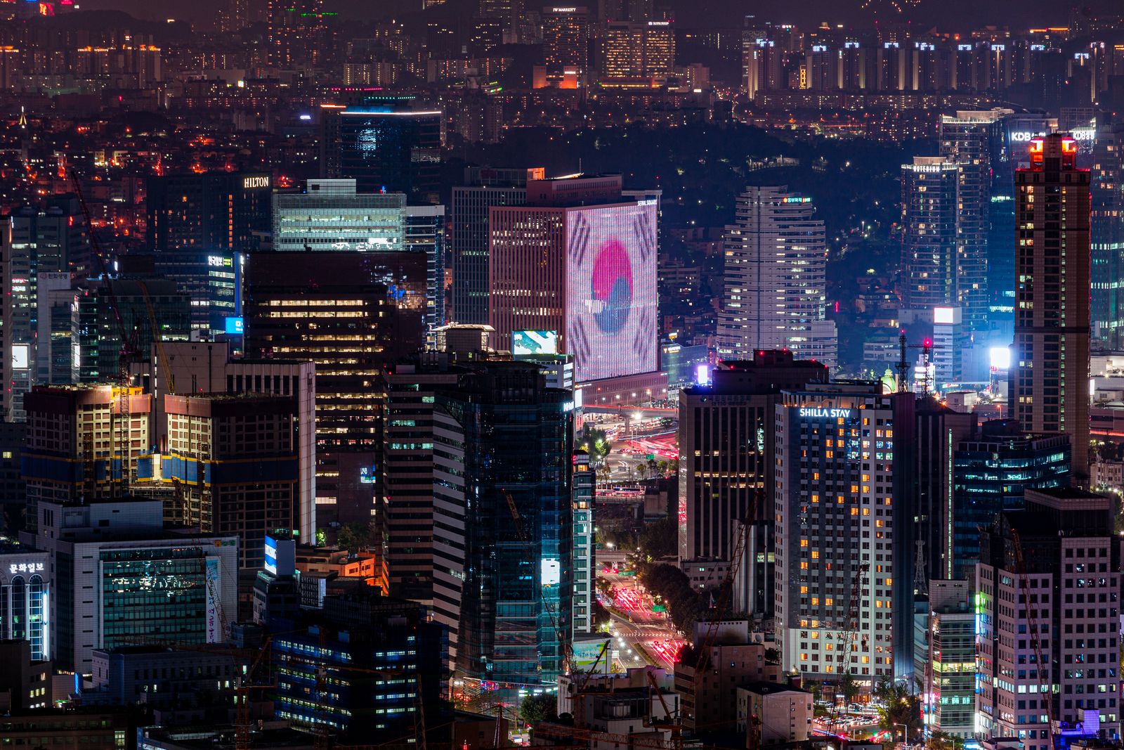 Vibrant night skyline of Seoul featuring illuminated skyscrapers and urban landscape.
