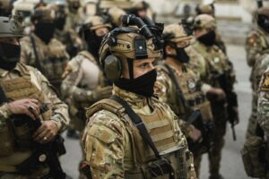 Group of soldiers in tactical gear standing in formation during a military operation.