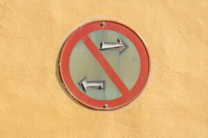 A weathered 'No Left Turn' traffic sign on a bright yellow wall, highlighting urban decay.
