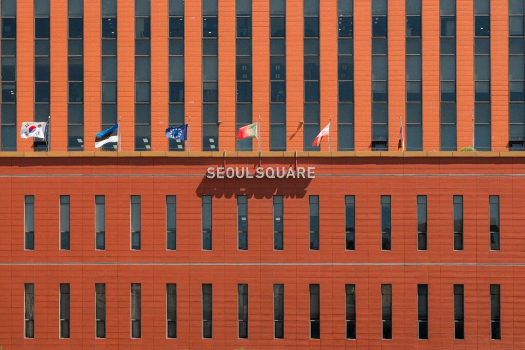 Red facade of Seoul Square with multiple international flags displayed.