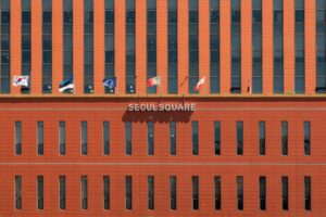 Red facade of Seoul Square with multiple international flags displayed.