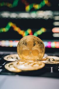 Gold Ripple coins on a laptop with a financial chart background, symbolizing digital currency trends.