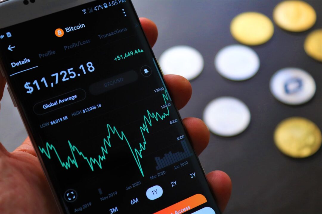 Close-up of Bitcoin trading app on smartphone showing market trends and digital coins.