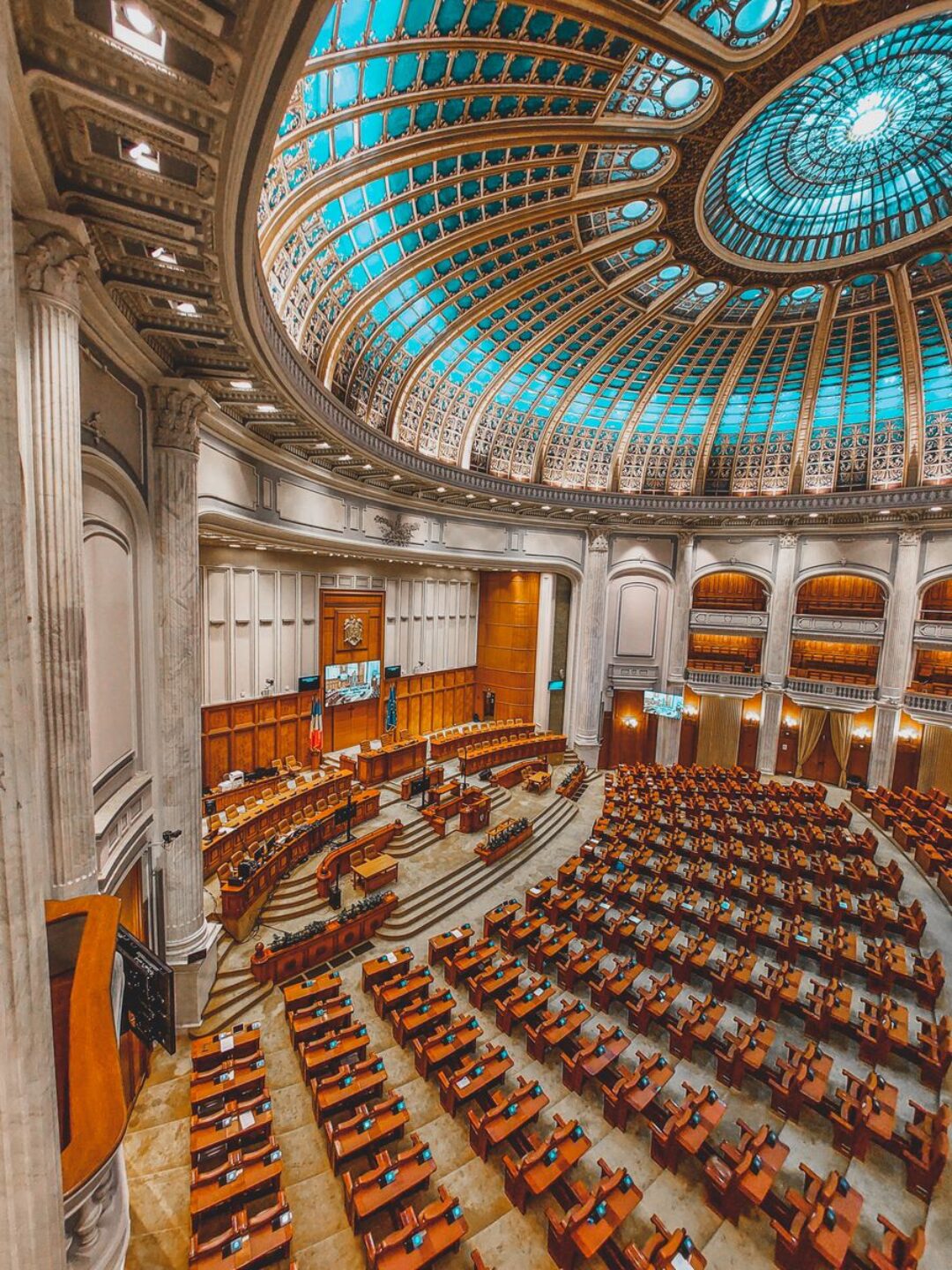 Stunning view of a grand neoclassical parliament chamber with intricate dome ceiling and seating arrangement.