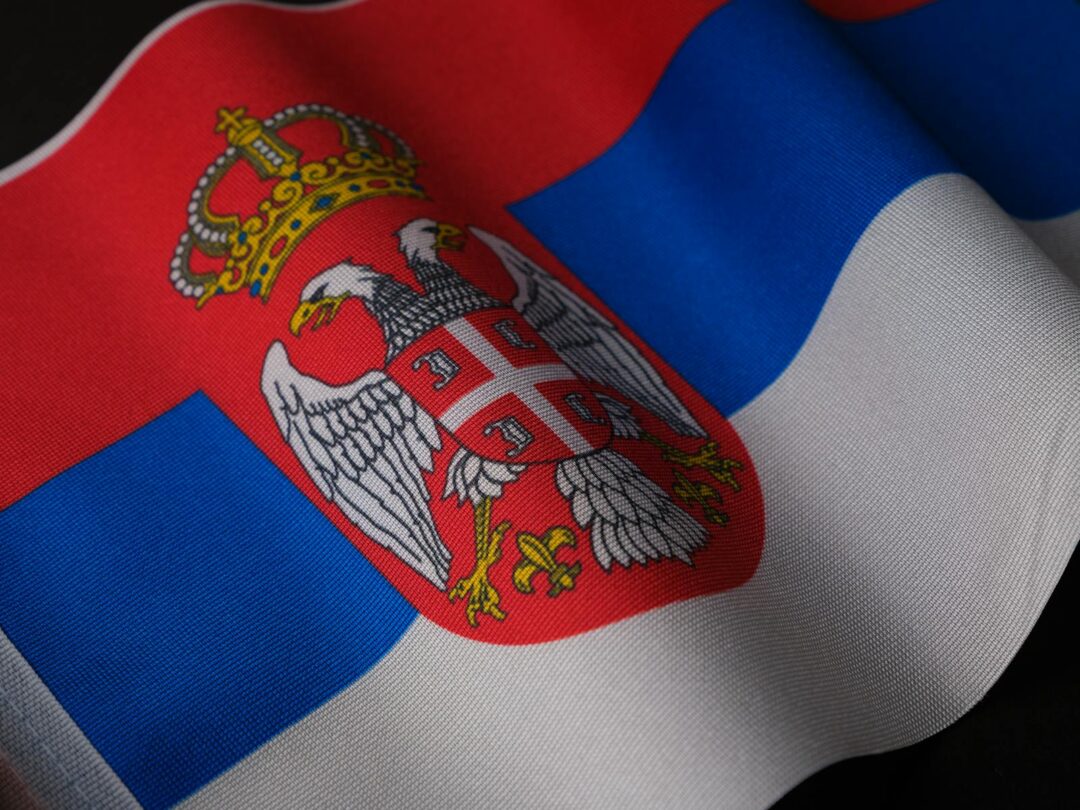 Close-up of the Serbian national flag showcasing its emblem and colors, symbolizing pride.