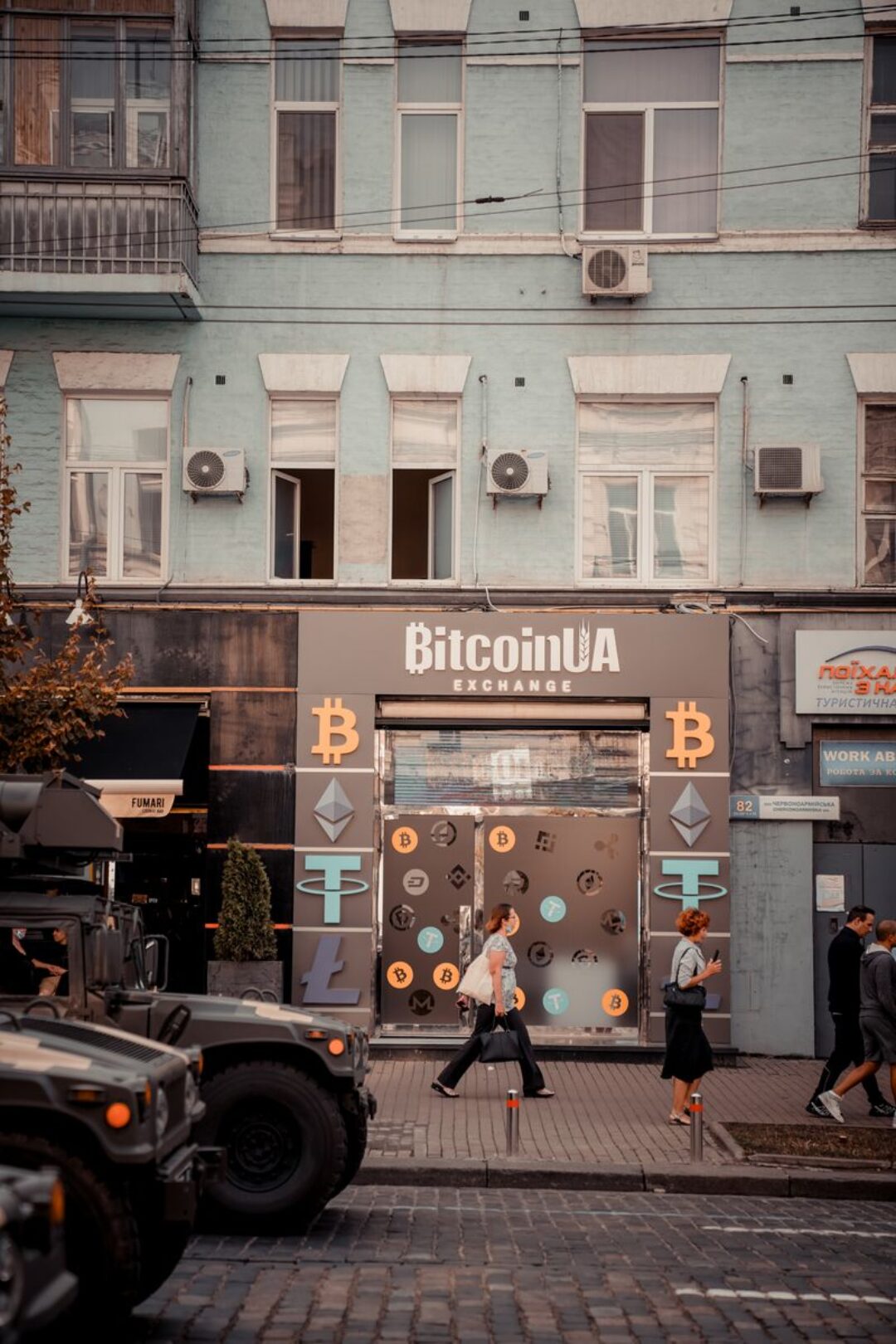 Busy city street with people passing by a Bitcoin exchange shop.
