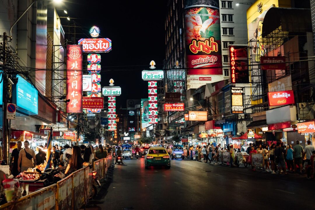 Bustling night scene on Yaowarat Road, Bangkok, showcasing vibrant street life and neon signs.