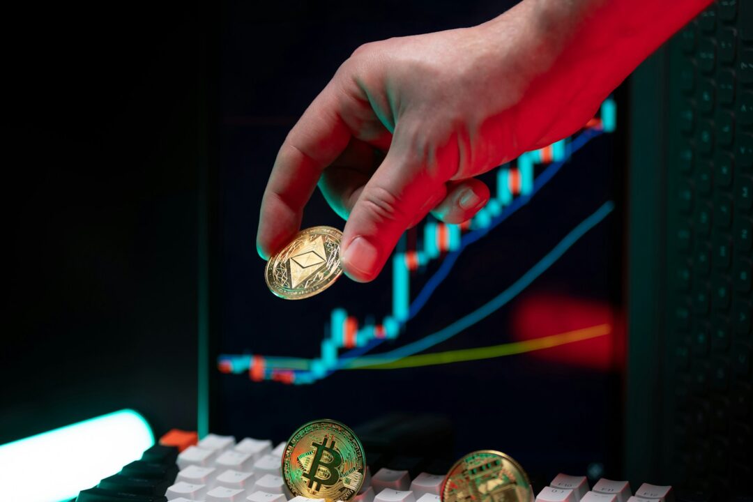 Hand holding ethereum with crypto graphs in background.