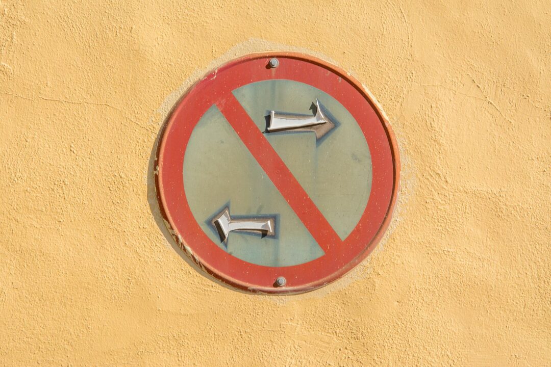 A weathered 'No Left Turn' traffic sign on a bright yellow wall, highlighting urban decay.