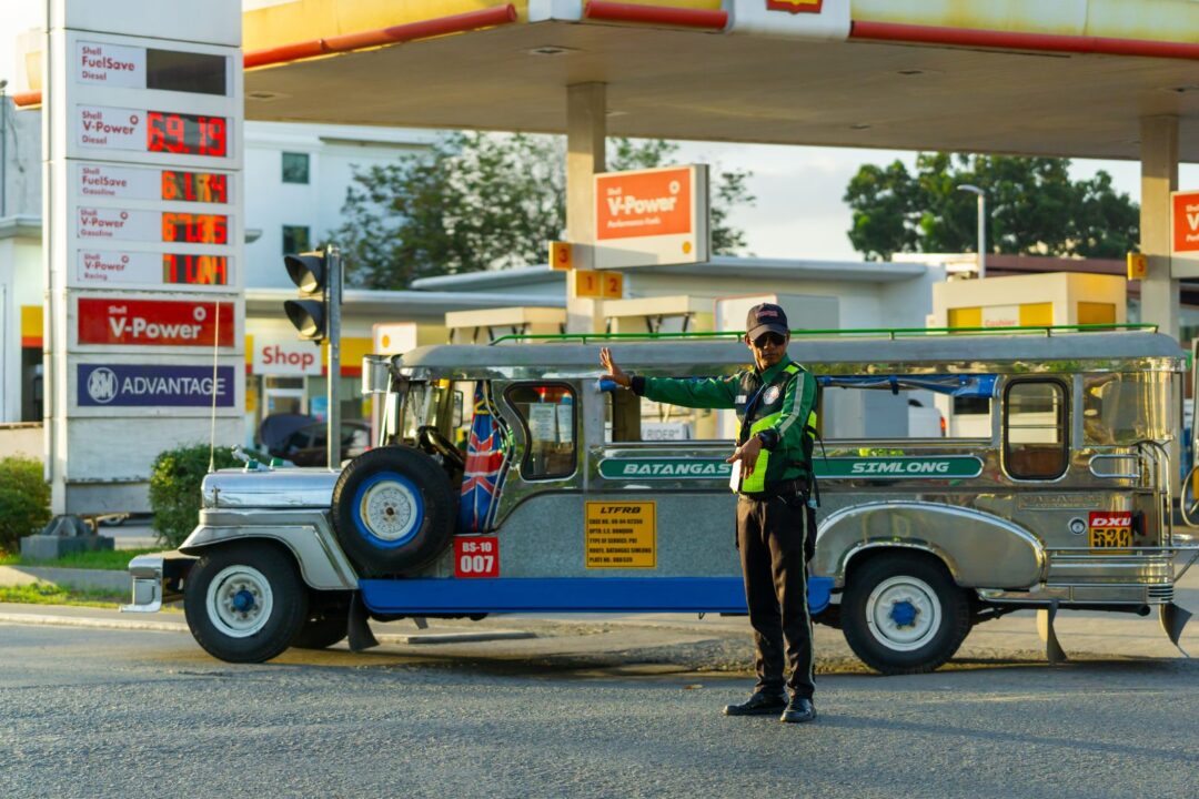 Traffic officer signals jeepney at a fuel station in the Philippines with clear weather and dynamic setting.