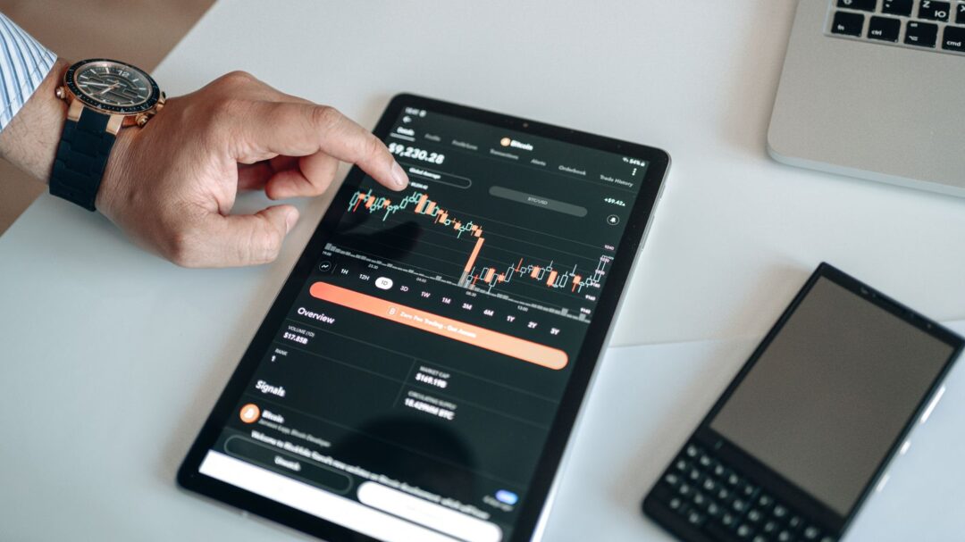 A person using a tablet to view and analyze a cryptocurrency market chart indoors.