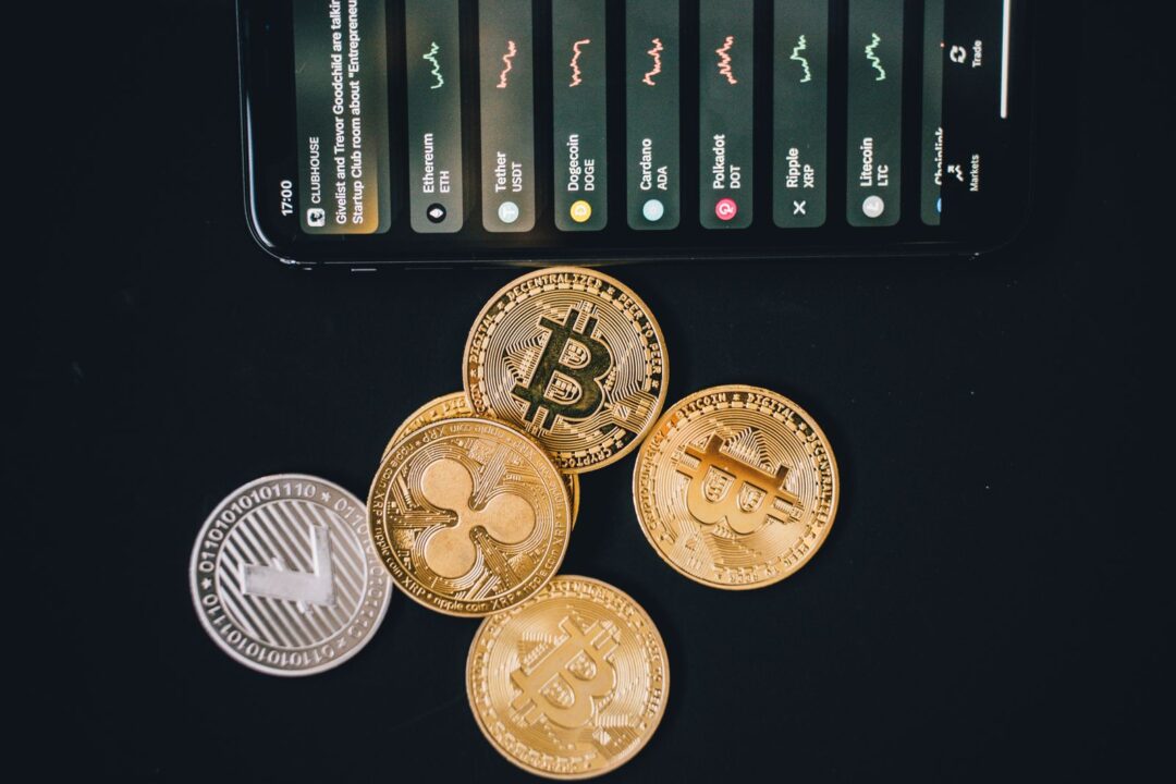 Close-up of various cryptocurrencies and a smartphone showing market trends.