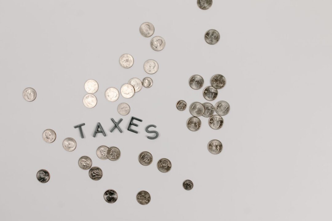 A visually striking flatlay of coins with 'Taxes' text on a white surface, ideal for financial concepts.