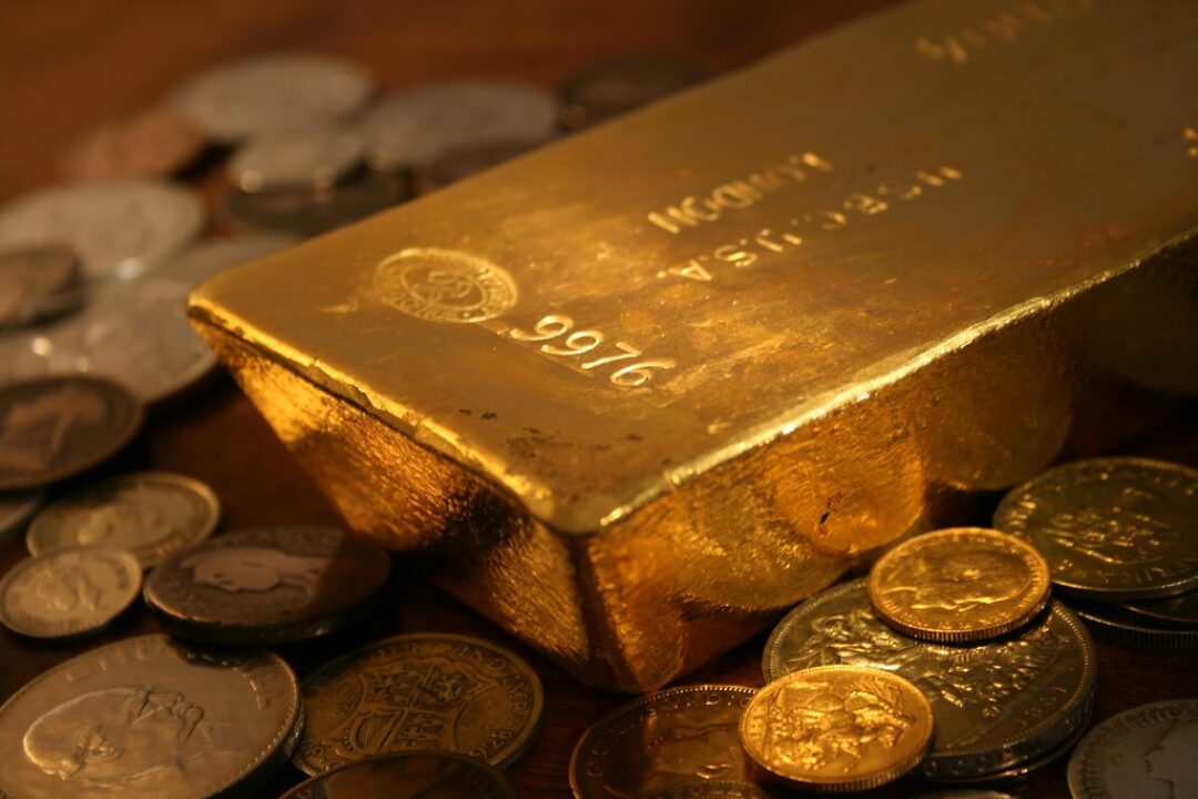 Shiny gold bar reflecting coins
