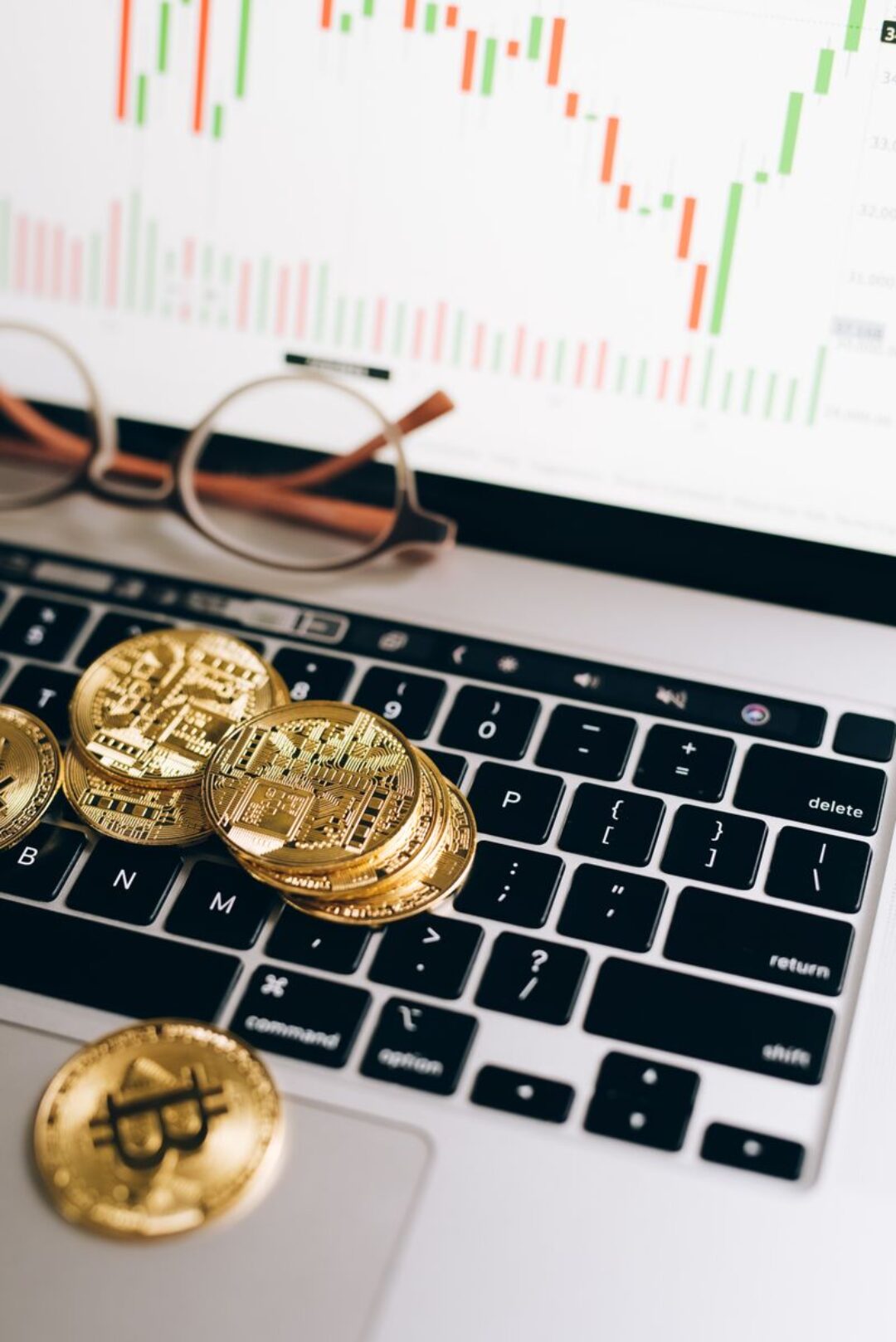 Gold bitcoins on a laptop with a financial chart, symbolizing cryptocurrency and investment trends.