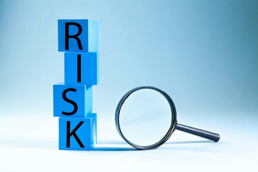 Blue blocks spelling risk next to a magnifying glass.