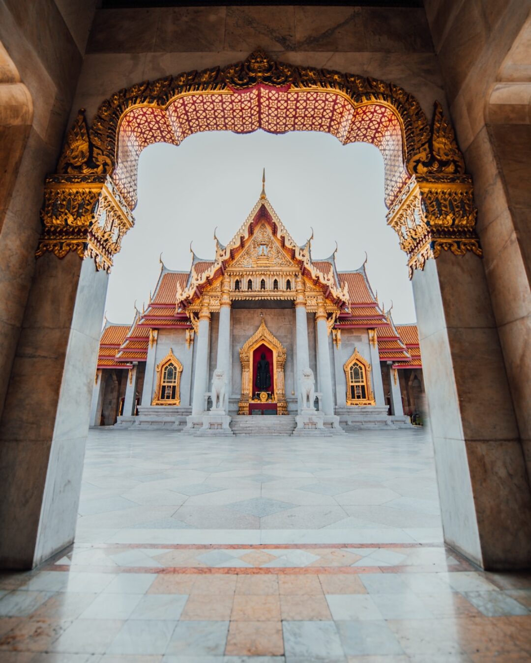 The Wat Benchamabophit temple framed by an ornate marble archway in Bangkok, Thailand